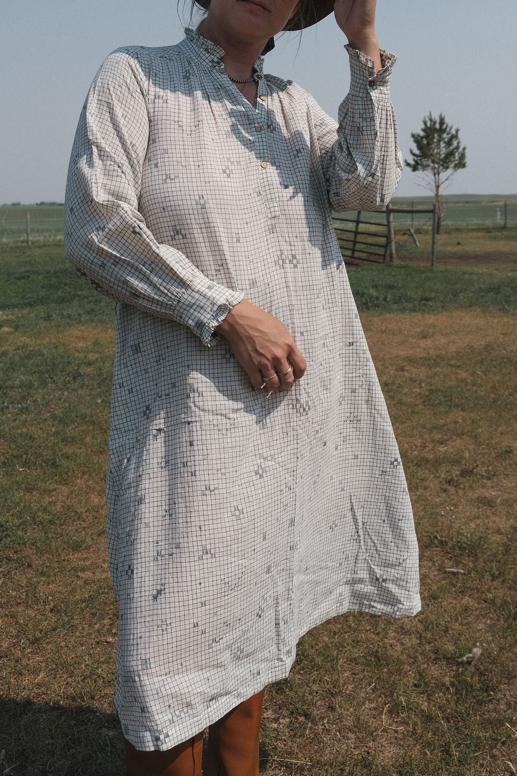 This Jamdani dress made with handwoven cotton is a perfect summer dress with its light color detailed square black threads. It has long sleeves with ruffles along a ruffled neck, and a midi length. 