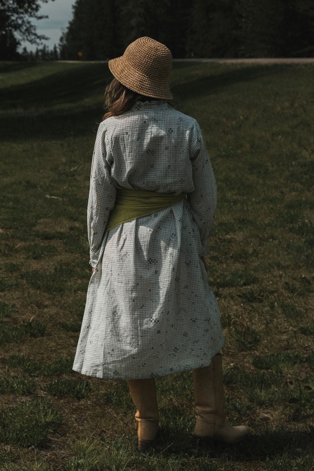 This Jamdani dress made with handwoven cotton is a perfect summer dress with its light color detailed square black threads. It has long sleeves with ruffles along a ruffled neck, and a midi length. 