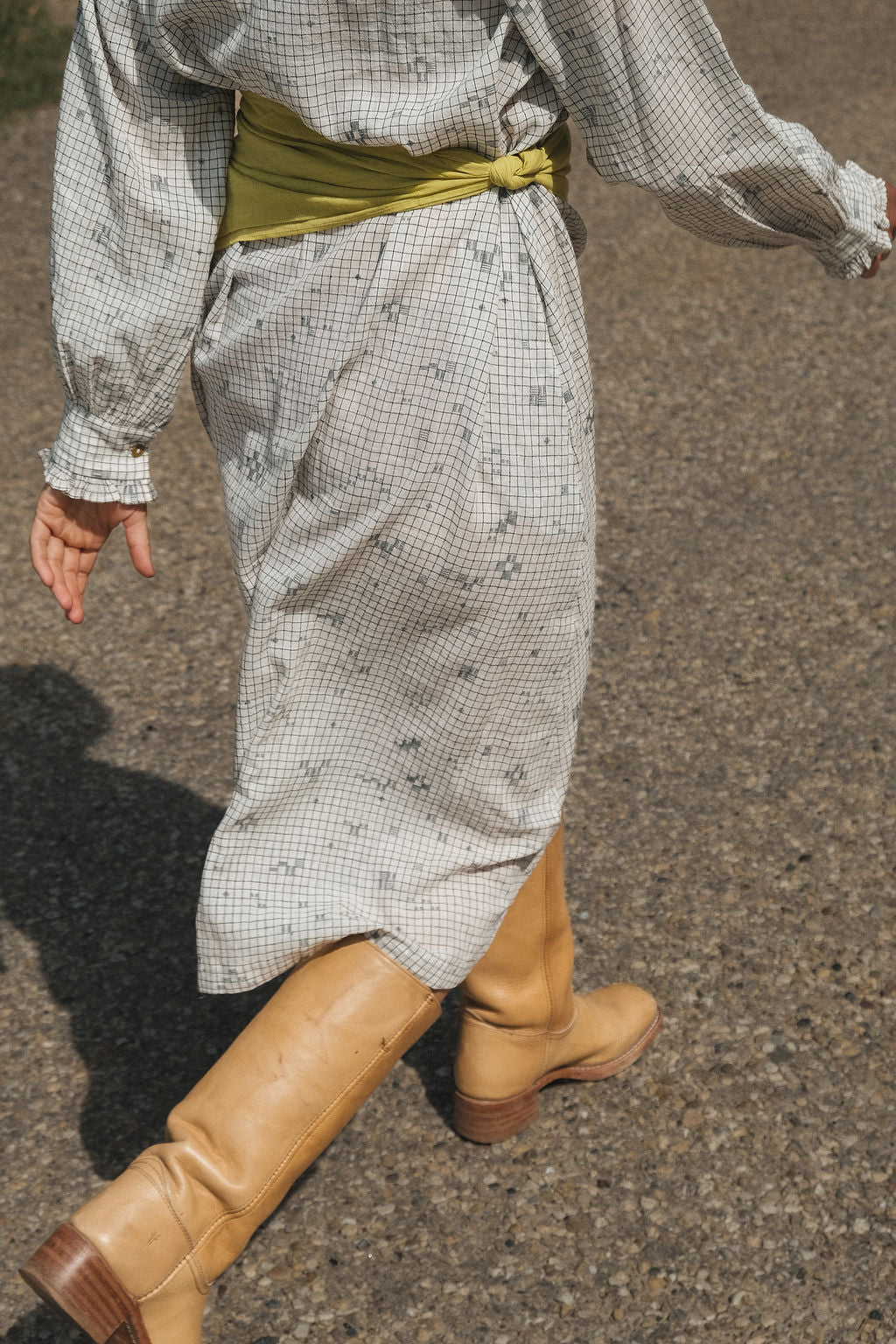 This Jamdani dress made with handwoven cotton is a perfect summer dress with its light color detailed square black threads. It has long sleeves with ruffles along a ruffled neck, and a midi length. 