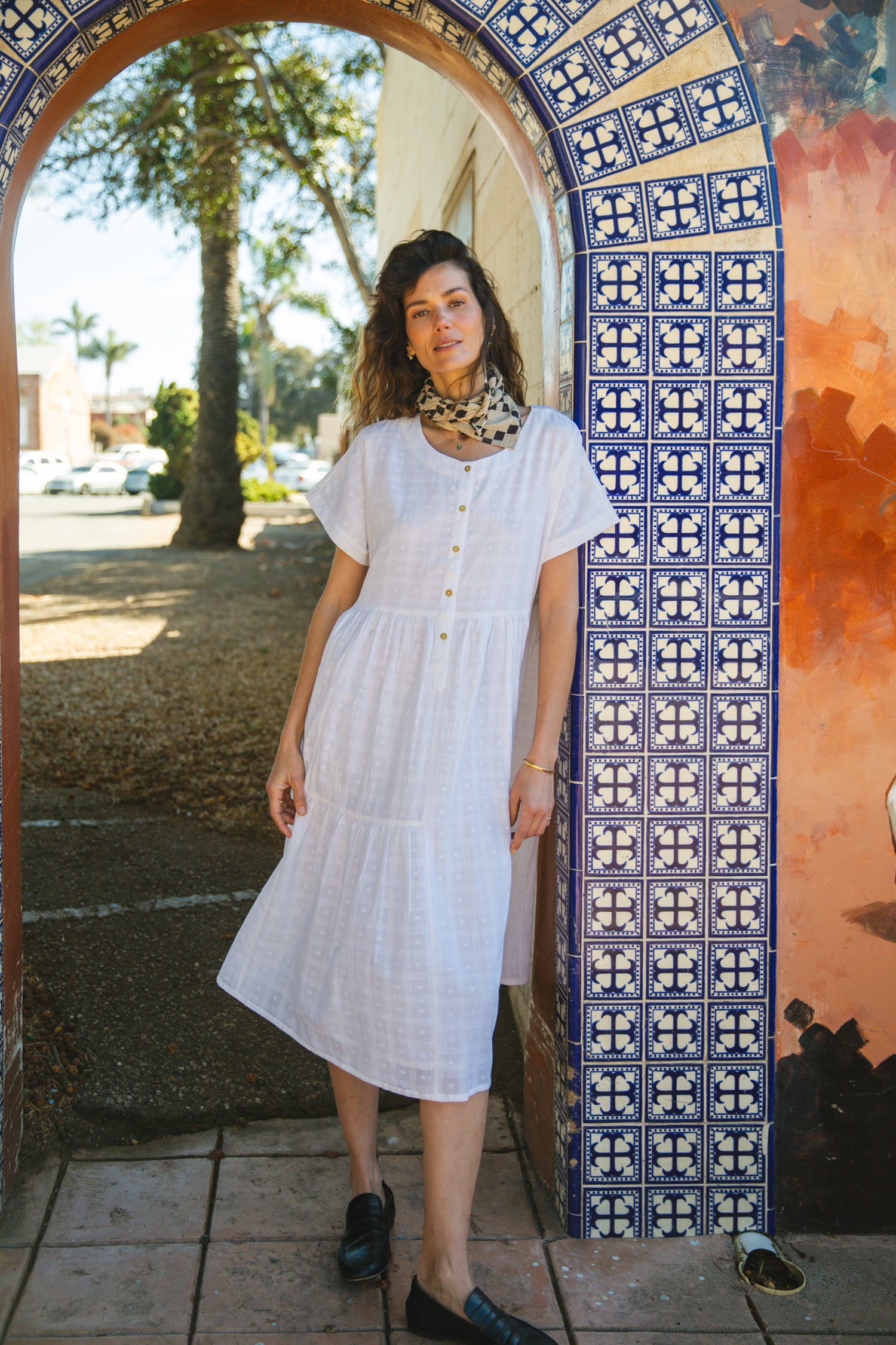 White A-line midi dress with cap sleeves, a button-down front, a gathered waist, it has delicate checks adding a texture to the garment. Made from lightweight, breathable fabric for a relaxed fit.