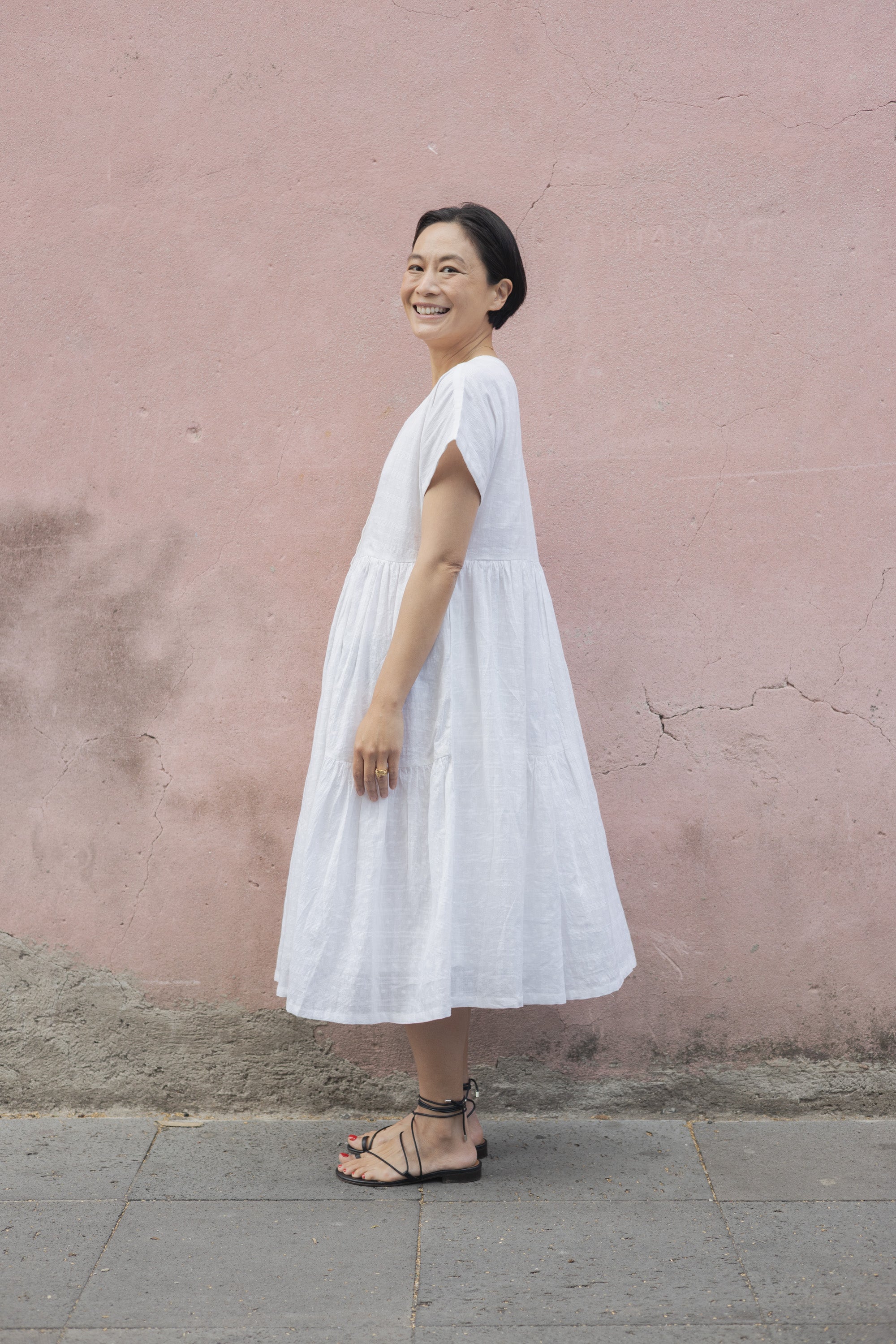 White A-line midi dress with cap sleeves, a button-down front, a gathered waist, it has delicate checks adding a texture to the garment. Made from lightweight, breathable fabric for a relaxed fit.